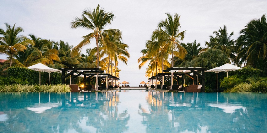 Pool inside a resort with multiple lounge chairs in the middle and resort buildings.
