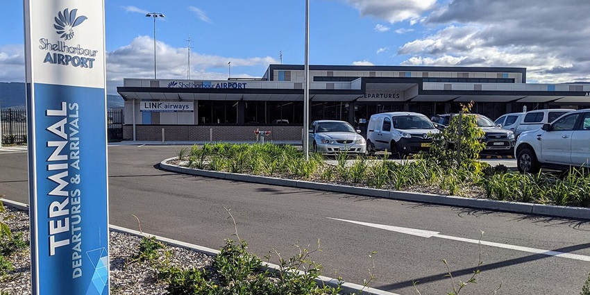 The Shellharbour Airport terminal with vehicles parked and clouds drifting above.