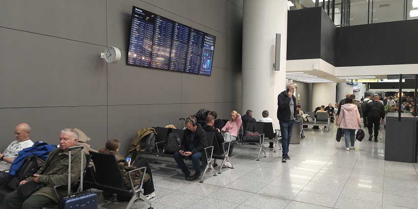 People sitting and passing by in Sheremetyevo Airport Terminal B in the waiting area.