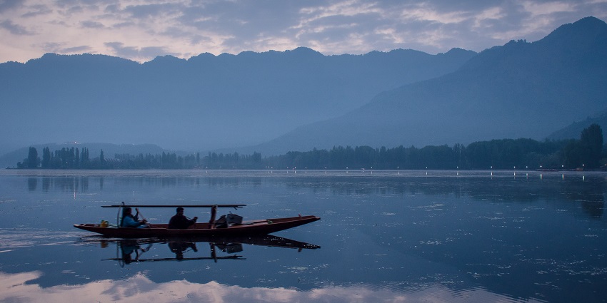 A picture of a Shikara gliding over the semi-frozen Dal Lake in December
