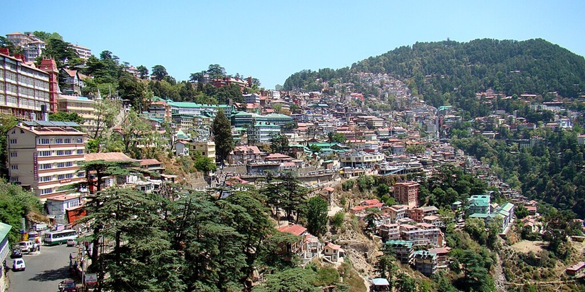 An image of the tall white church in Shimla, with Gothic arches, spires, clock tower, and moody overcast sky.