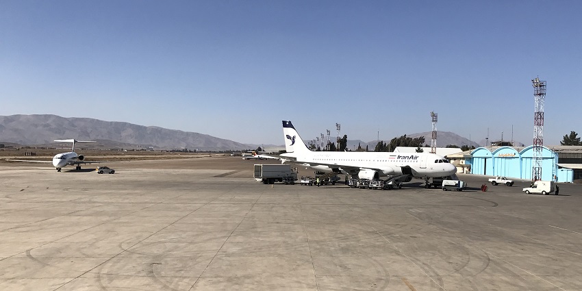 IranAir aeroplane parked next to the terminal building, and another aeroplane parked at a distance.