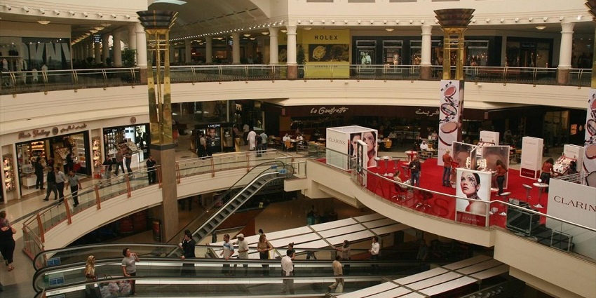 Interior of Deira City Centre with escalators, beauty displays, and elegant decor.