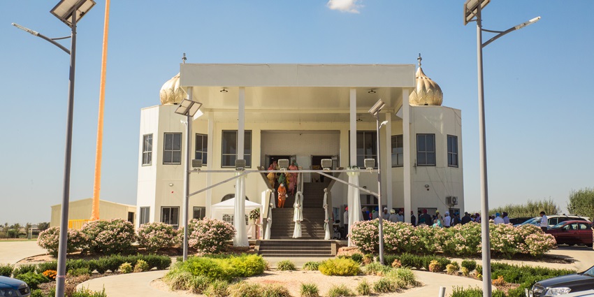 Gurudwara sahib with people on the stairs leading to the gurudwara and solar street lights