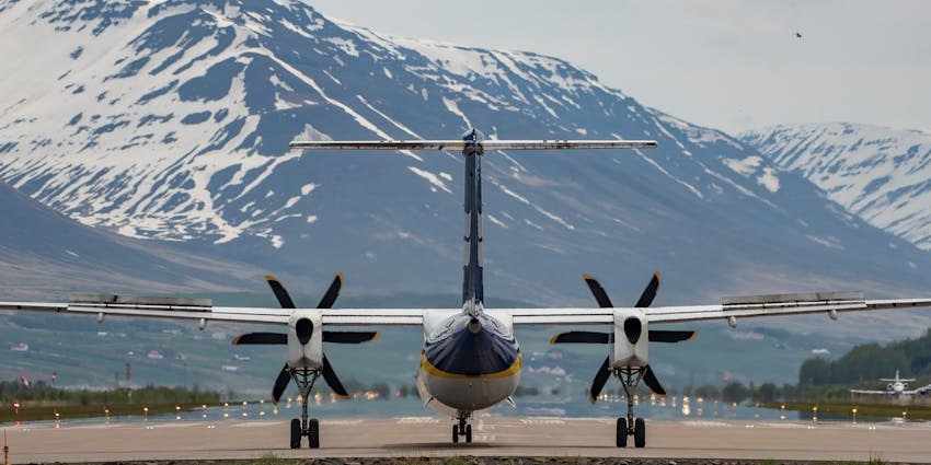 An aeroplane in Siglufjörður Airport in Iceland, with a backdrop of towering mountains.