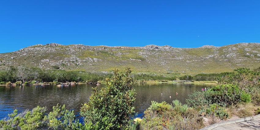 View of Silvermine Nature Reserve with green mountains and a calm reservoir in Cape Town.