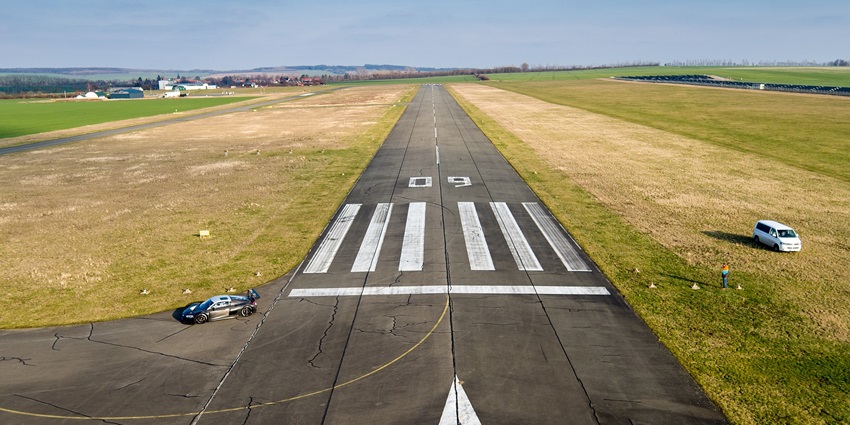 Empty runway of an airport with vast stretches of green and yellow fields on both sides