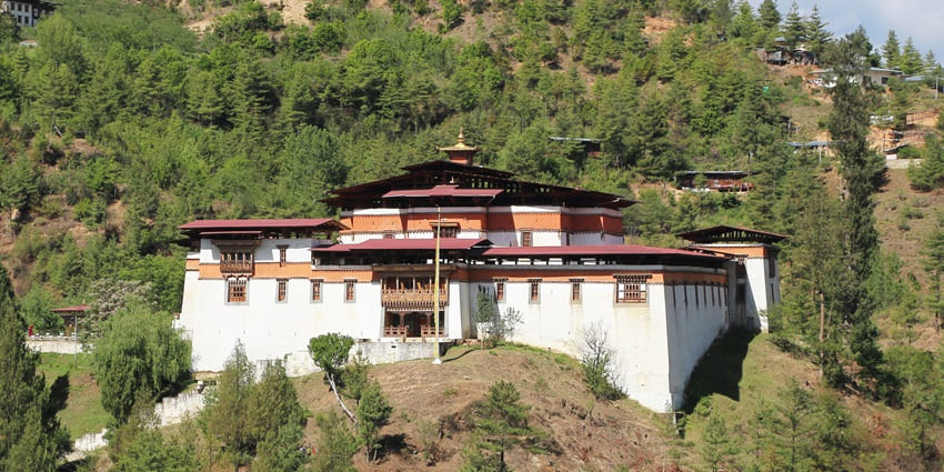 The oldest fortress in Bhutan, standing proudly with its white walls and red roofs against a blue sky.