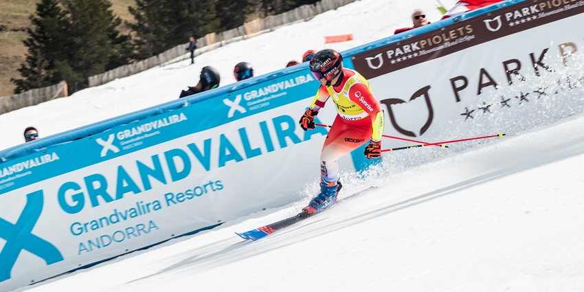 A professional skier is gliding down the snowy slope while skillfully manoeuvring.