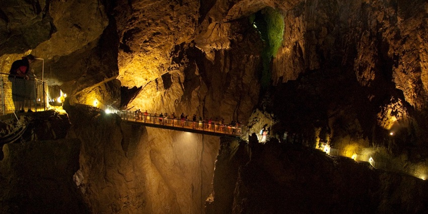 Visitors walking on a lit bridge, surrounded by the beauty of Škocjan Caves in Slovenia