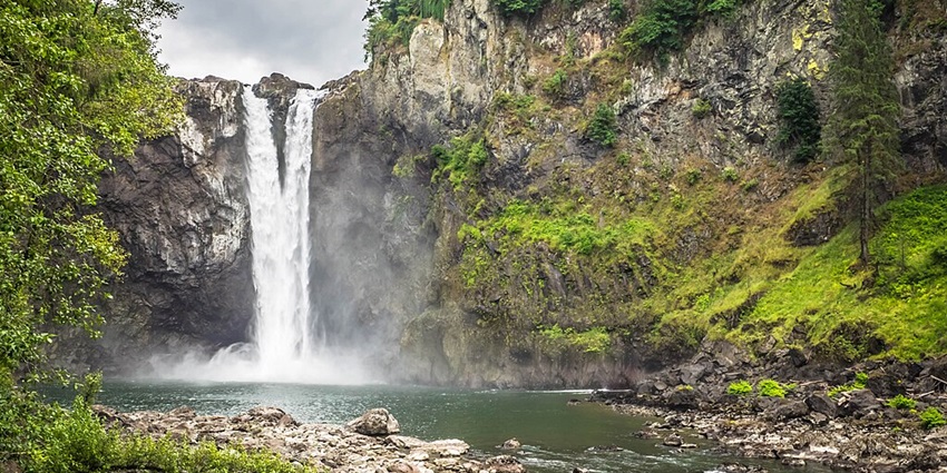A breathtaking 268-foot waterfall in Washington, surrounded by mist and evergreen forests.
