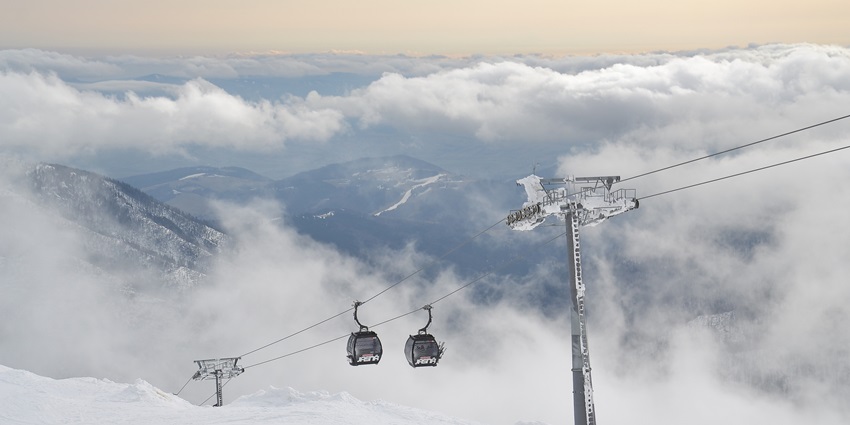A ski resort with fluffs of white snow eclipsing the entire scenery and cable cars hanging by