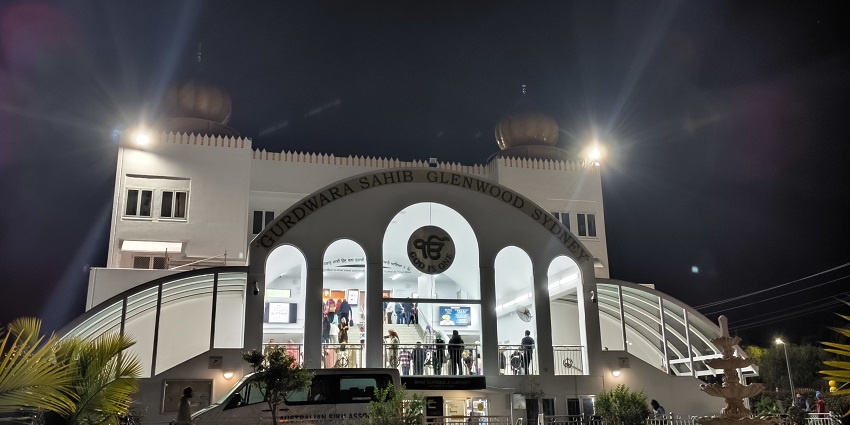 Gurdwara in Sydney bustling with people, two lights and a van parked outside.