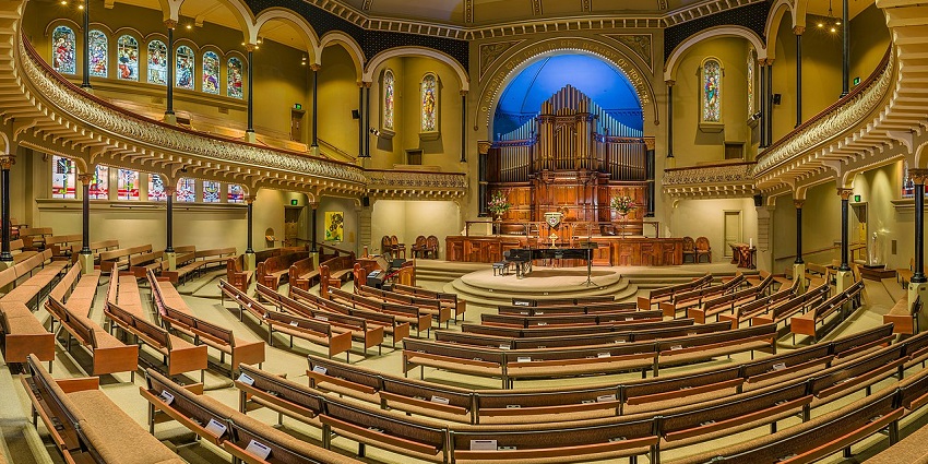 Inside of St Michael's Church illuminated with yellow lights and empty hall with benches.