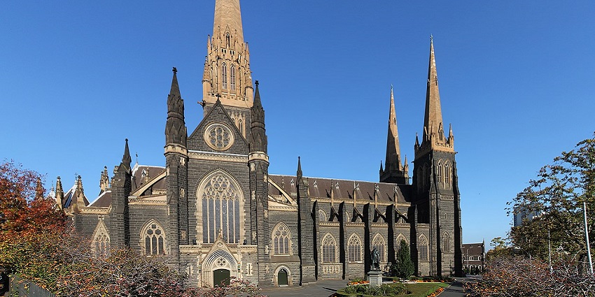 St. Patrick's Cathedral, Melbourne, gothic spires, stone building, clear sky, green lawn.