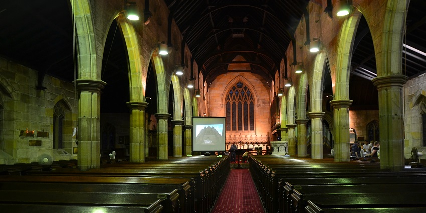 Interior of St. John's Anglican Church with beautiful lighting and few people on the right side