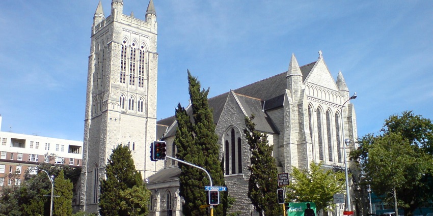 St Matthew-in-the-City, Auckland, with Gothic arches, cars, and people in motion around it