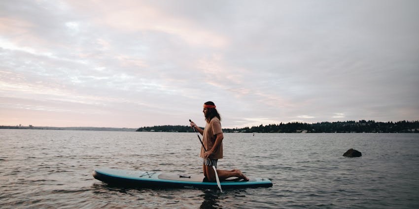 People during paddle boarding enjoy the view of the river and hill, one of the best water sports in Australia.