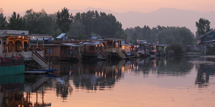 Multiple houseboats in the lake with small lamps on the houseboats in the evening