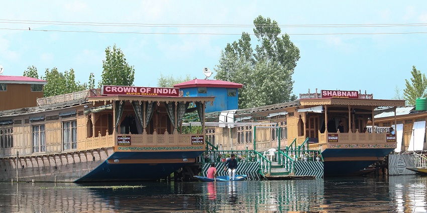 Couple of houseboats with signage, windows on the boat, stairs and people on the boat