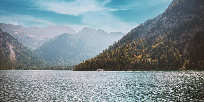 An image of Surinsar Lake with its surrounding green hills and blue waters.