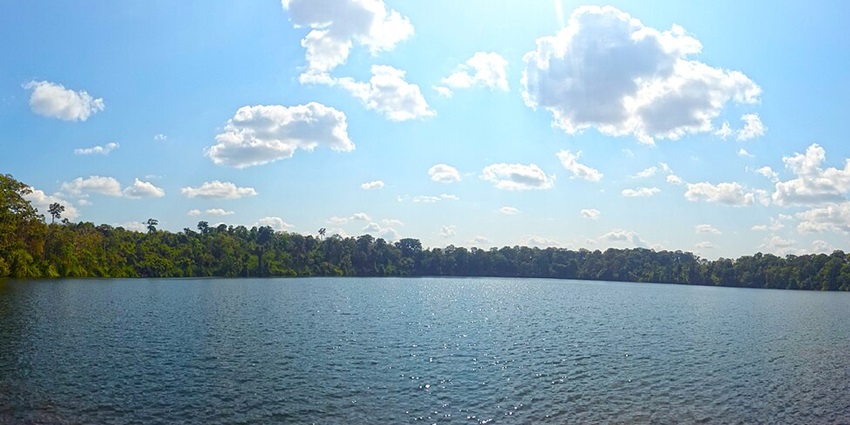 Yeak Laom Volcanic Lake, a circular lake surrounded by dense trees and wooden walkways.