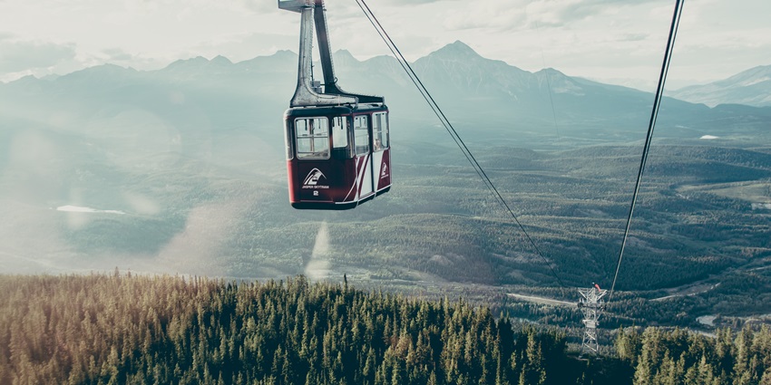 A ski track and mountains stretching in the distance covered in snow with skiers zig-zagging