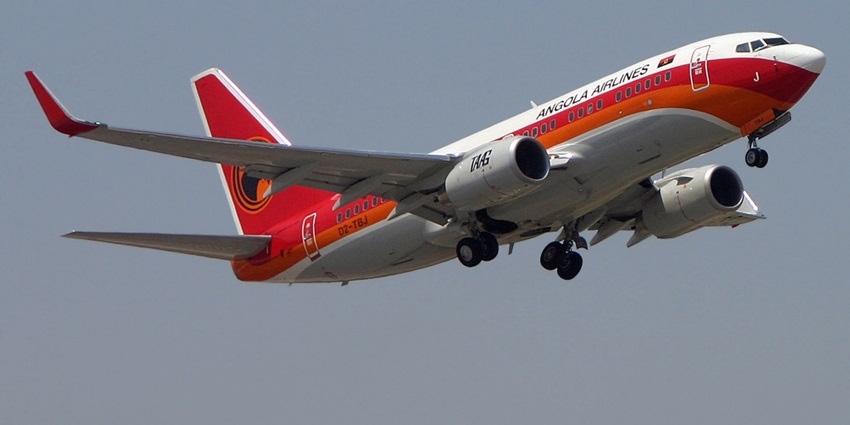 Aeroplane in red, orange, and white is flying gracefully through a clear blue sky with no trail