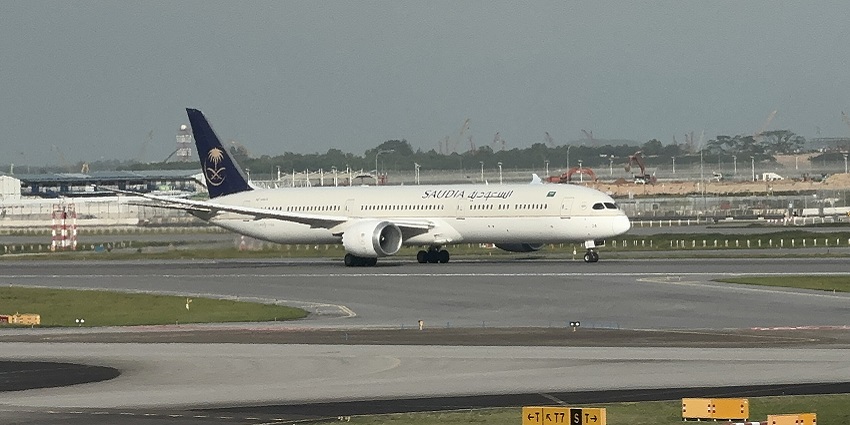 Saudia HZ-AR24 commercial aeroplane on the runway with signages and distant buildings