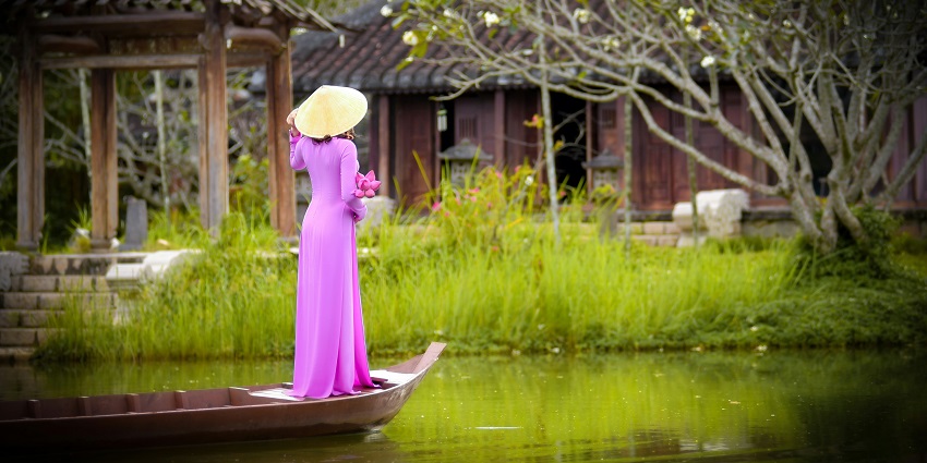 A woman in a pink dress on a boat in Hoi An, one of the romantic things to do in Hoi An.