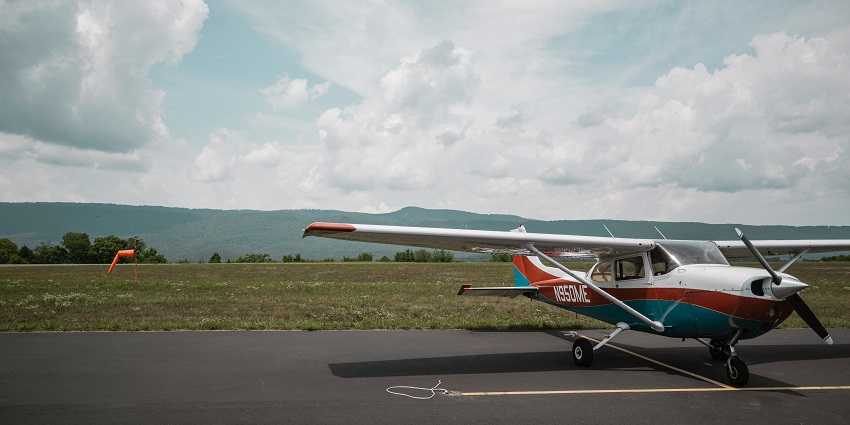 View of a small single-engine airplane, used for Aircraft Joyride, parked near a grassy field