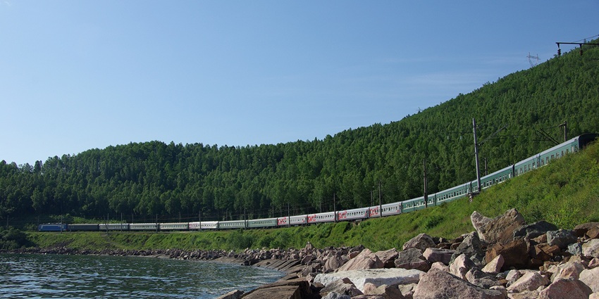 Train passing through the Circum-Baikal railway with Lake Baikal, rocky shores and mountains.