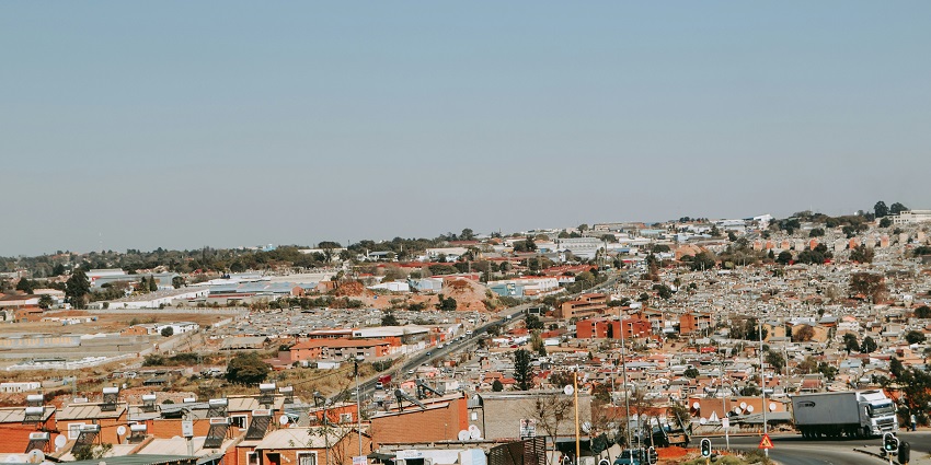 A view of Soweto, with cars, road signs, and a densely packed residential area nearby.