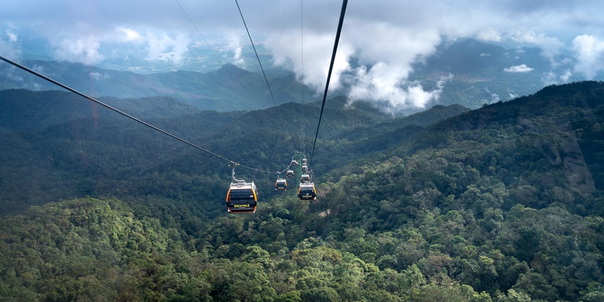 A cable car suspended in mid-air, offering spectacular views of the Ba Na Hills landscape.