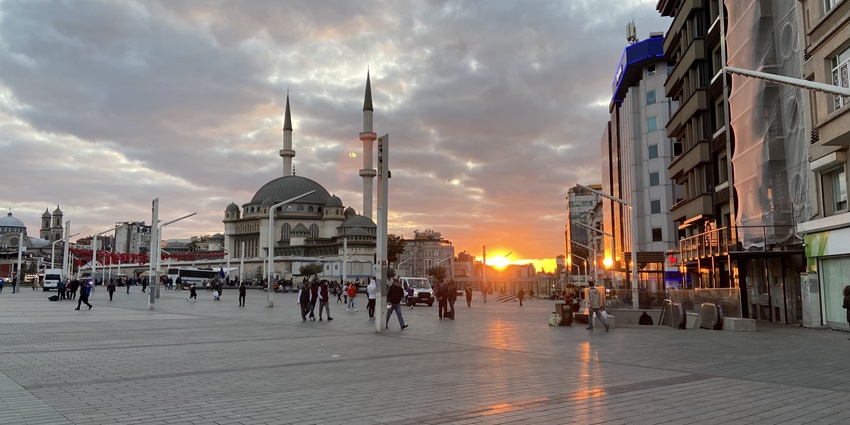 A picture of Taksim Square bustling with people and historic monuments.