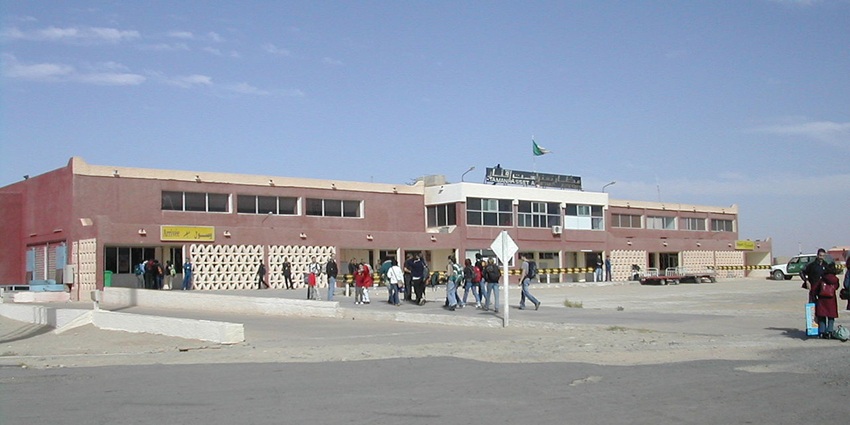 Terminal entrance of Tamanrasset airport with multiple passengers entering the terminal