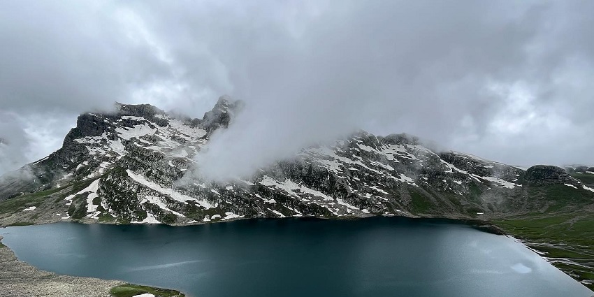 Tarsar lake with a large frozen body surrounded by small, partially snow-covered hills