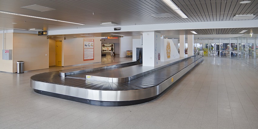 Inside of an airport with empty halls and a baggage clearance equipment in the middle