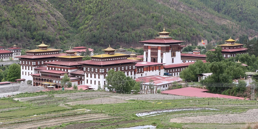 A serene view of the famous Tashichho Dzong surrounded by lush green vegetation.