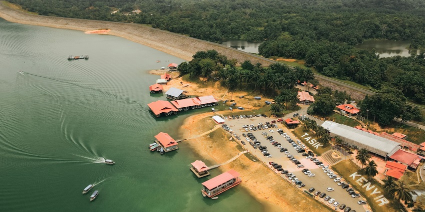 Aerial view of a lakeside parking lot surrounded by greenery and calm waters.