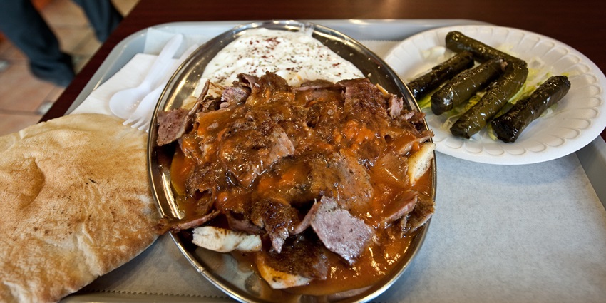 An image of İskender Kebab, a famous Turkish dish, featuring sliced meat with sauce and yogurt.