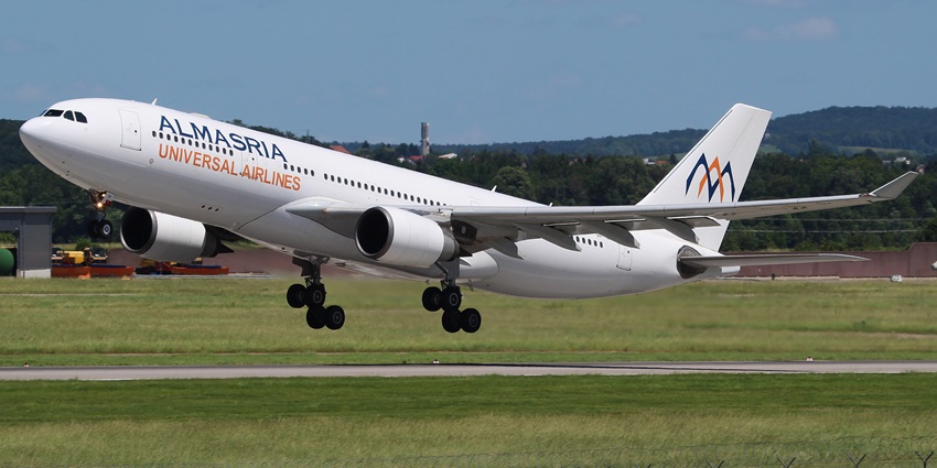White Airbus A330 aeroplane taking off from the runway at an airport with green plains