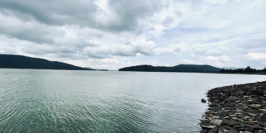 Lake with a clear and large water body, rocky shoreline and mountains at a distance