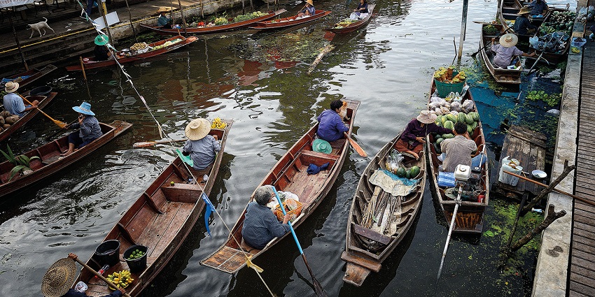 A picture of Tha Kha Floating Market, with locals selling fruits and vegetables from their wooden boats.
