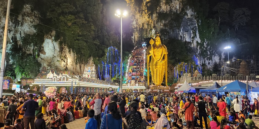 An image of a devotee having a piercing across his cheek, celebrating Thaipusam, and performing rituals with offerings.