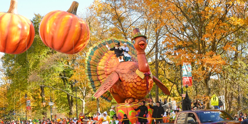 Giant festive cartoon balloon floats over New York City street during Macy’s Thanksgiving Parade