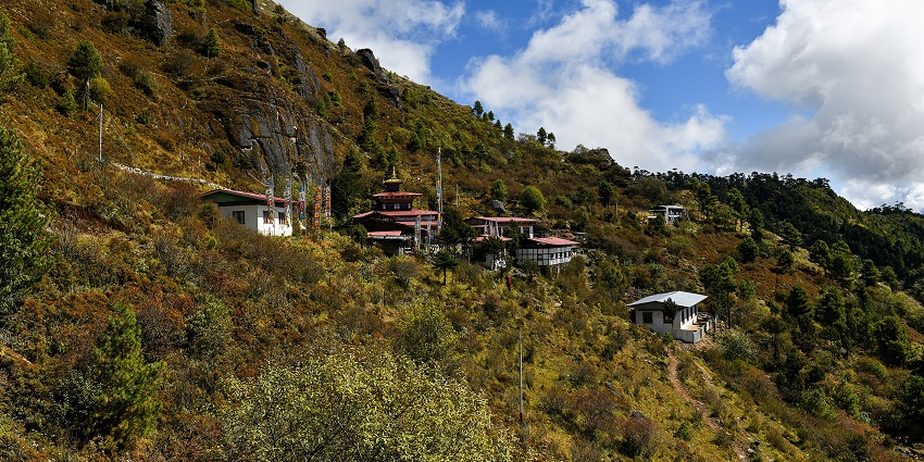 Image of a Buddhist monastery around the mountains coverd in lush greenery during day time view