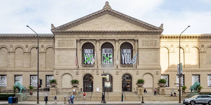 An image of Chicago's Art Institute facade, with columns, banners reading whimsical phrases, and lion statues.