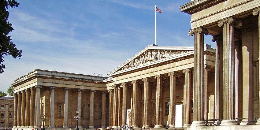 An image of the British Museum entrance, with neoclassical columns, pediment sculptures, and the Union Jack flying above.