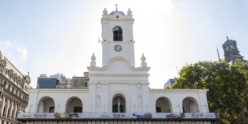 White building of the Cabildo of Buenos Aires surrounded by other buildings on a busy day.